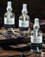 3 clear hydrosol spray bottles on a wooden table with lavender branches sprawled across